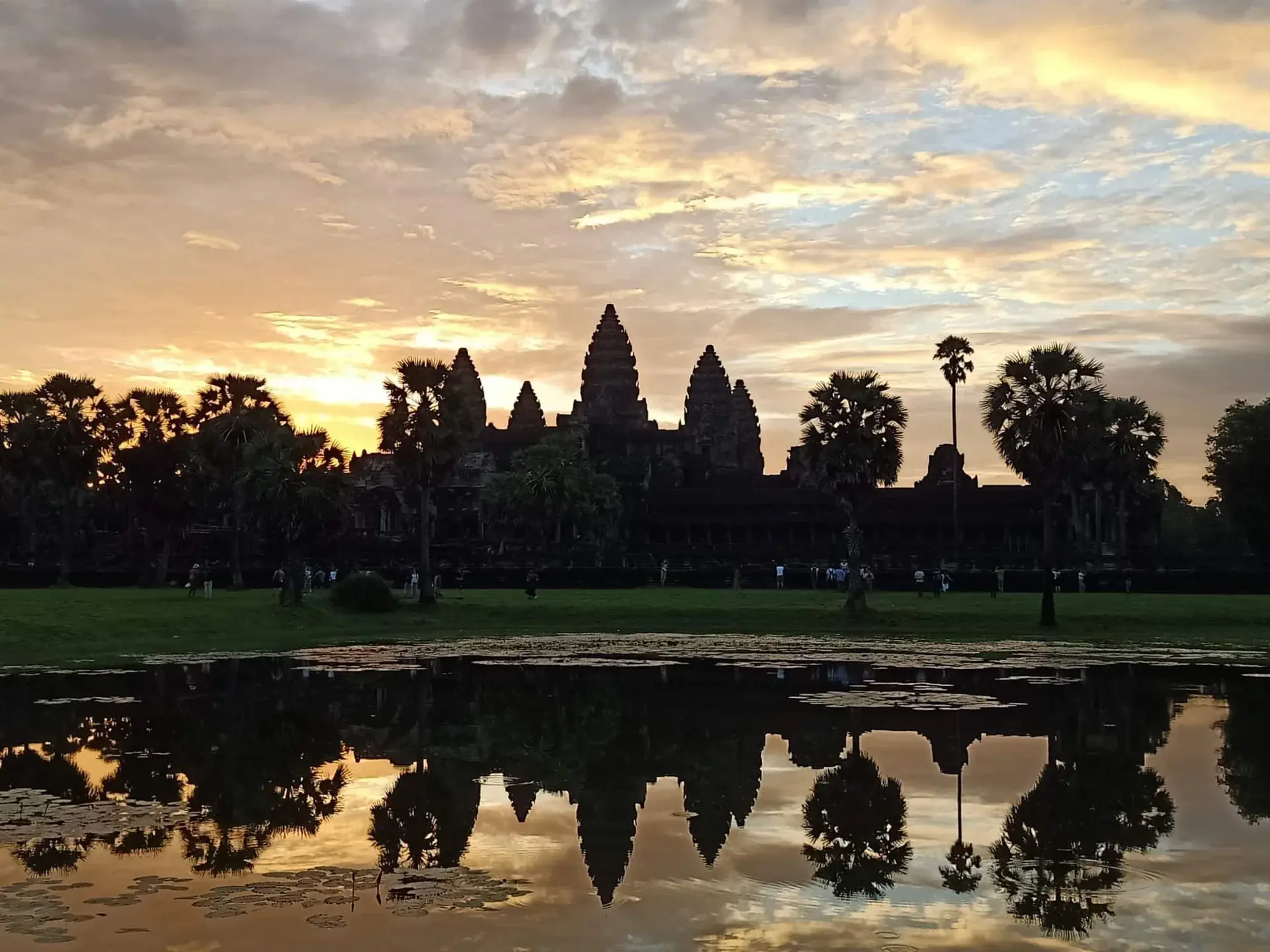 Stunning sunrise at Angkor Wat with the temple silhouette and five towers reflected in the tranquil waters of the moat