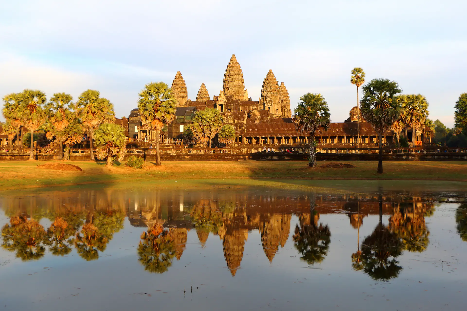 Majestic view of Angkor Wat temple complex showing the iconic five-tower silhouette and surrounding moat under blue skies