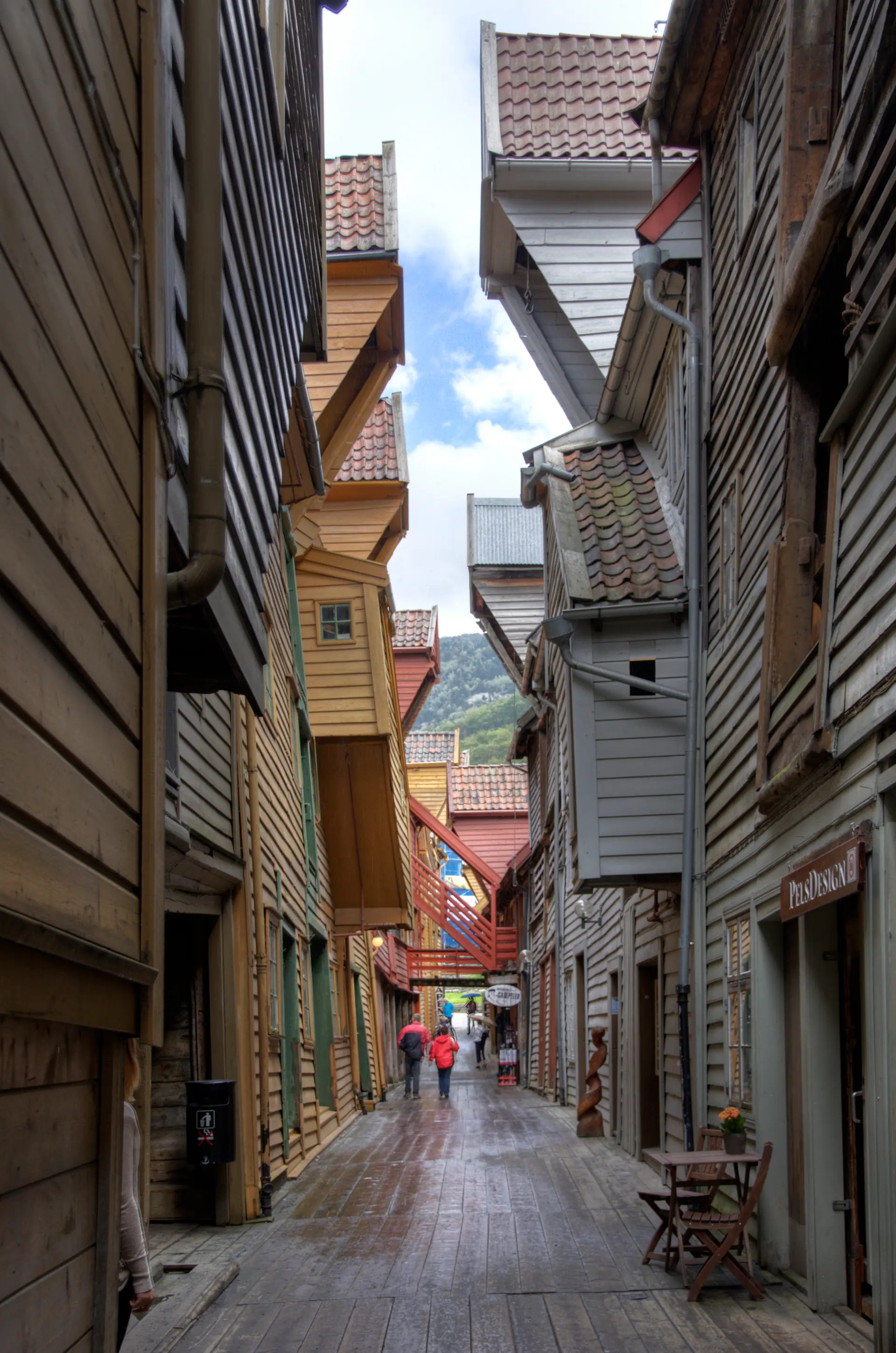 Narrow medieval alleyway between wooden buildings at Bryggen with cobblestone path and atmospheric lighting