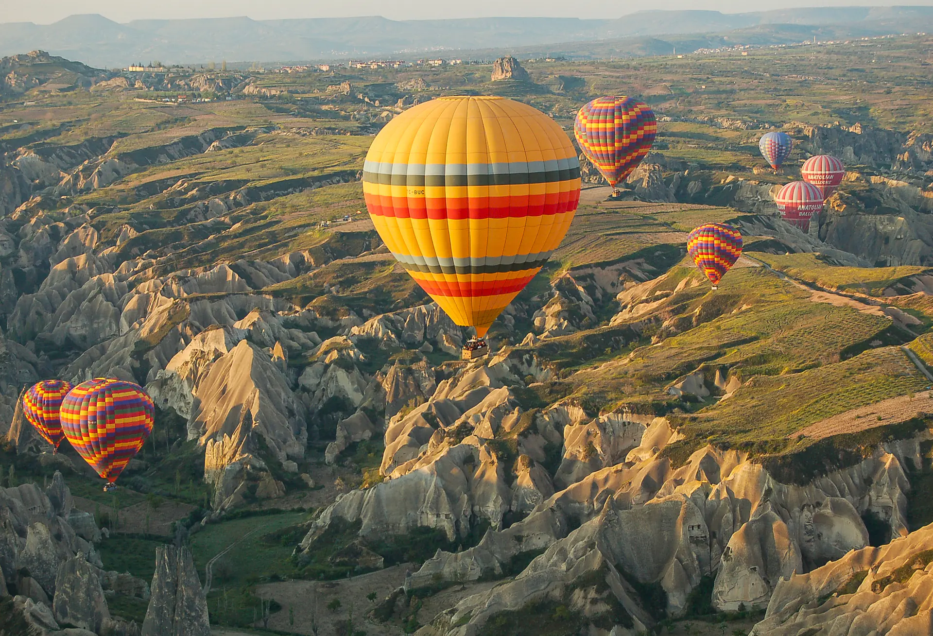 Colourful hot air balloons floating above Cappadocia's fairy chimney rock formations at sunrise