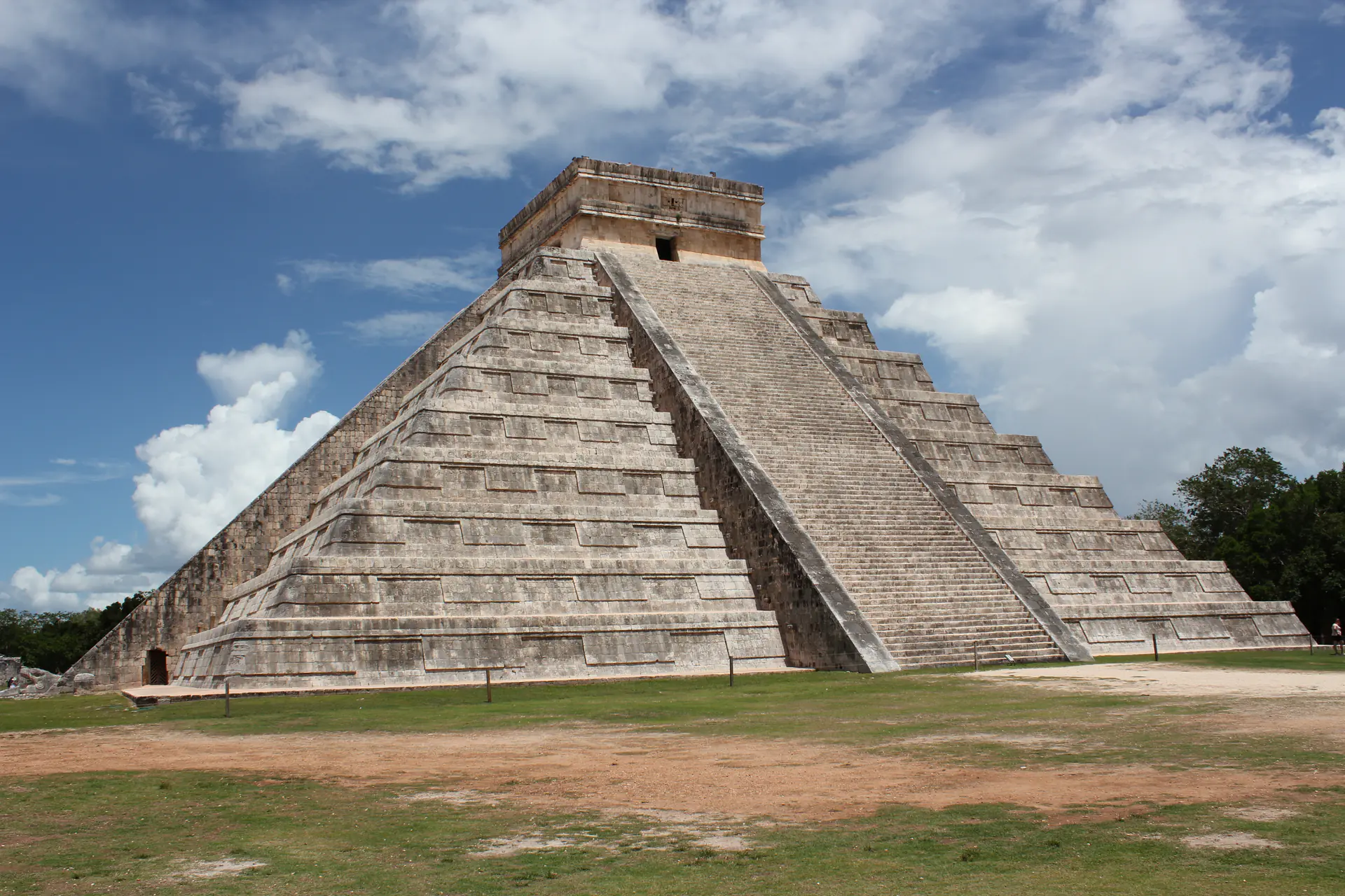 Majestic view of El Castillo pyramid at Chichen Itza showing the western facade with detailed stepped architecture against blue sky