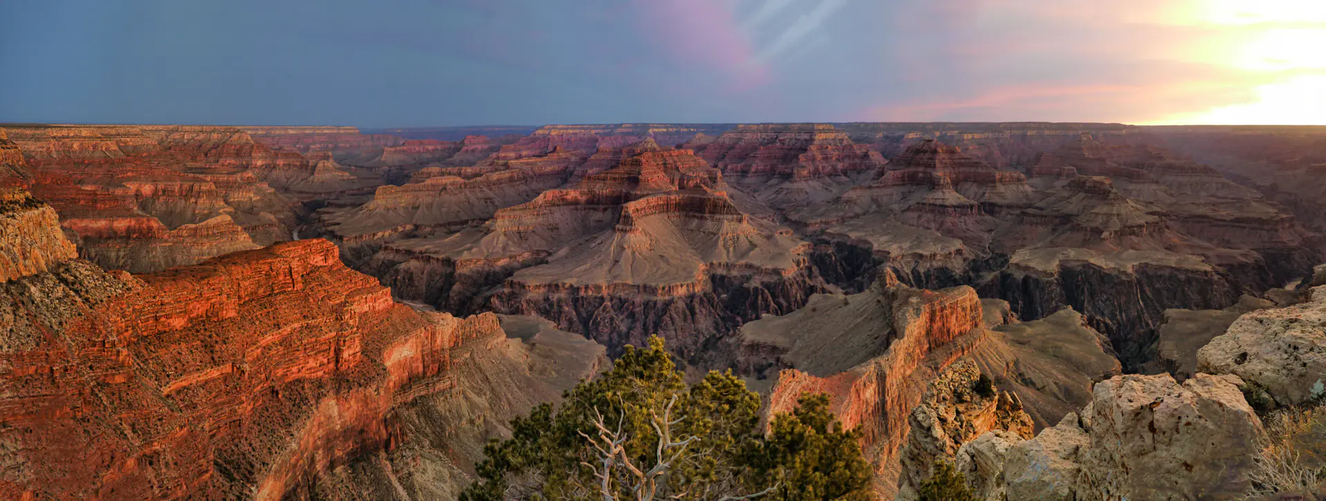 Sweeping panoramic view of Grand Canyon showcasing layered rock formations, vast depths, and dramatic geological features