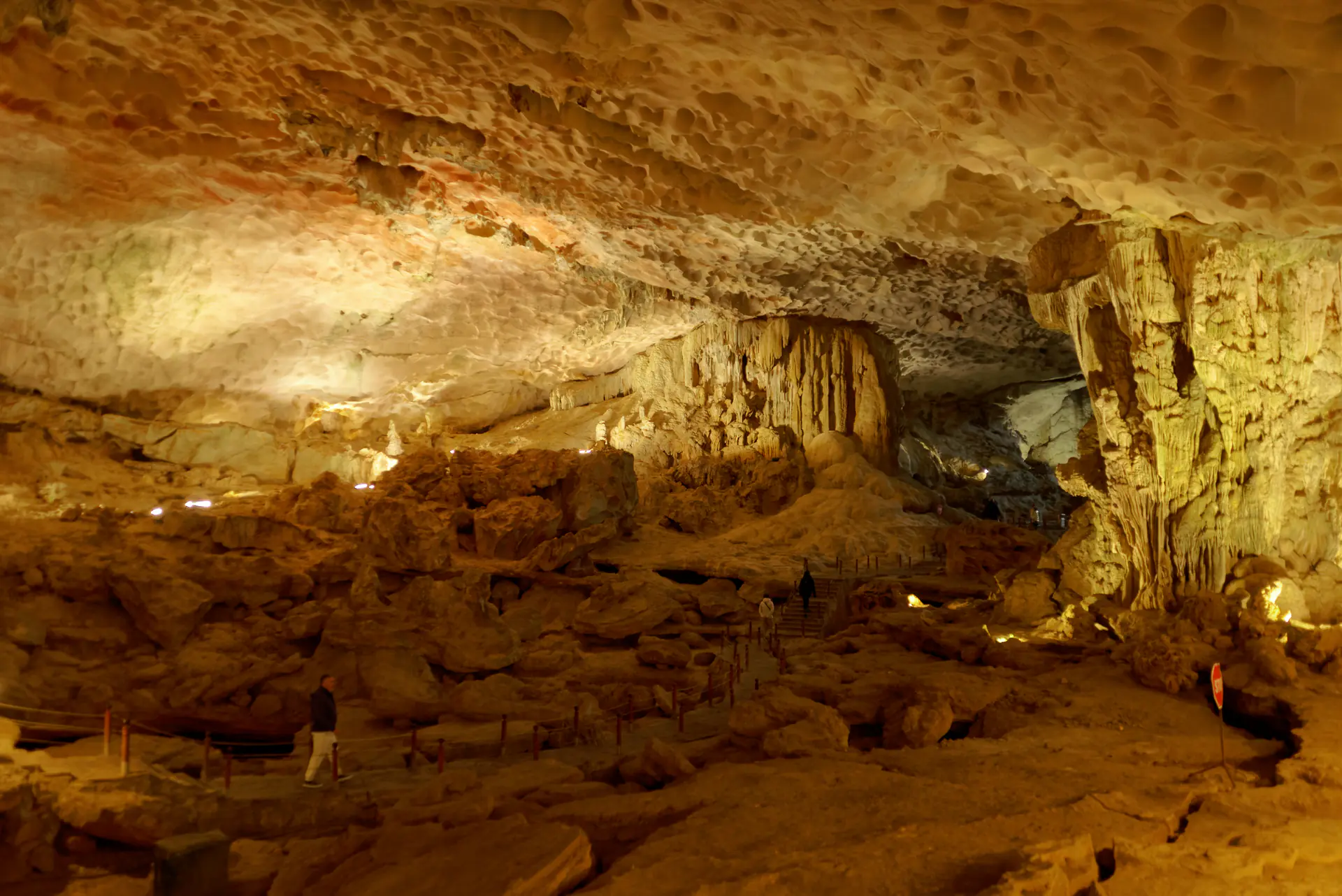 Vista interior de la Cueva Sung Sot mostrando cámaras masivas con estalactitas y estalagmitas iluminadas creando formaciones geológicas dramáticas