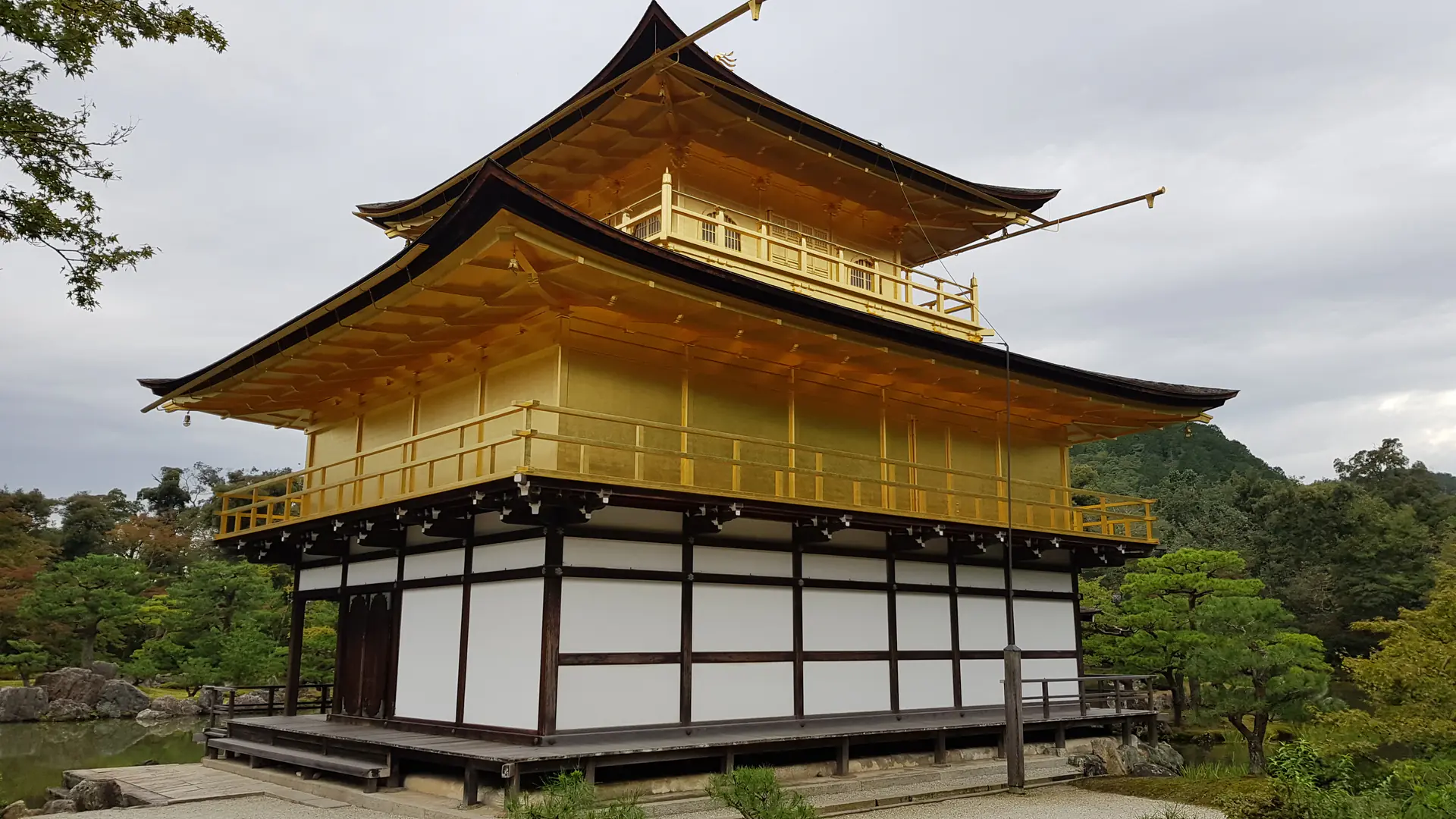 Close-up view of Kinkaku-ji Golden Pavilion showcasing the intricate gold-leaf-covered architecture and detailed craftsmanship of the upper stories