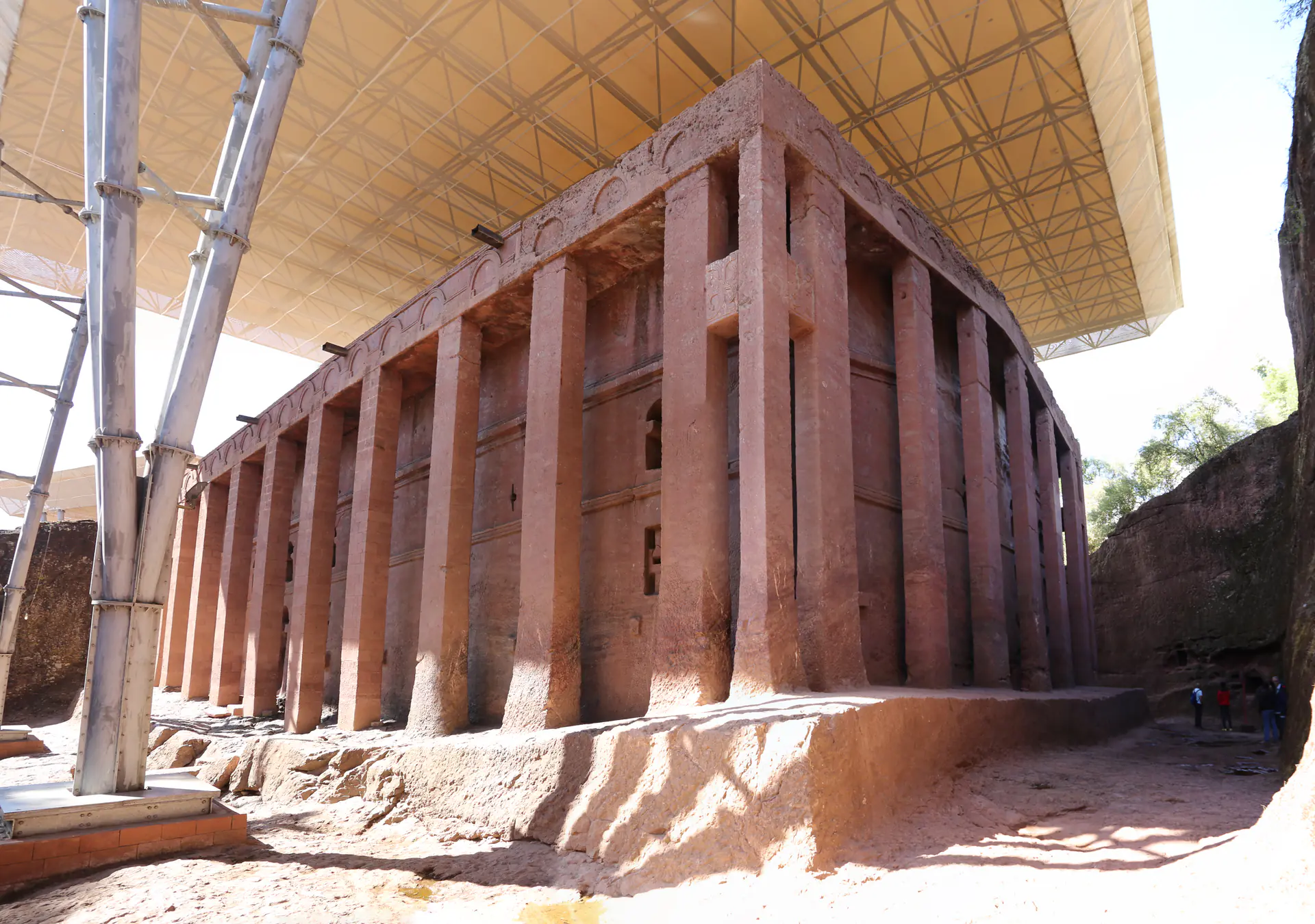 Exterior facade of Bet Medhane Alem showing the massive colonnade of carved stone pillars supporting the rock-hewn church, the largest monolithic church in the world