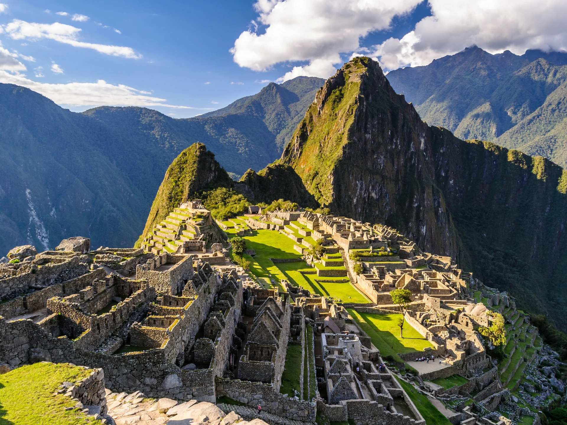Panoramic view of the Machu Picchu archaeological citadel with its ancient stone terraces and structures set against the dramatic Andean mountain landscape