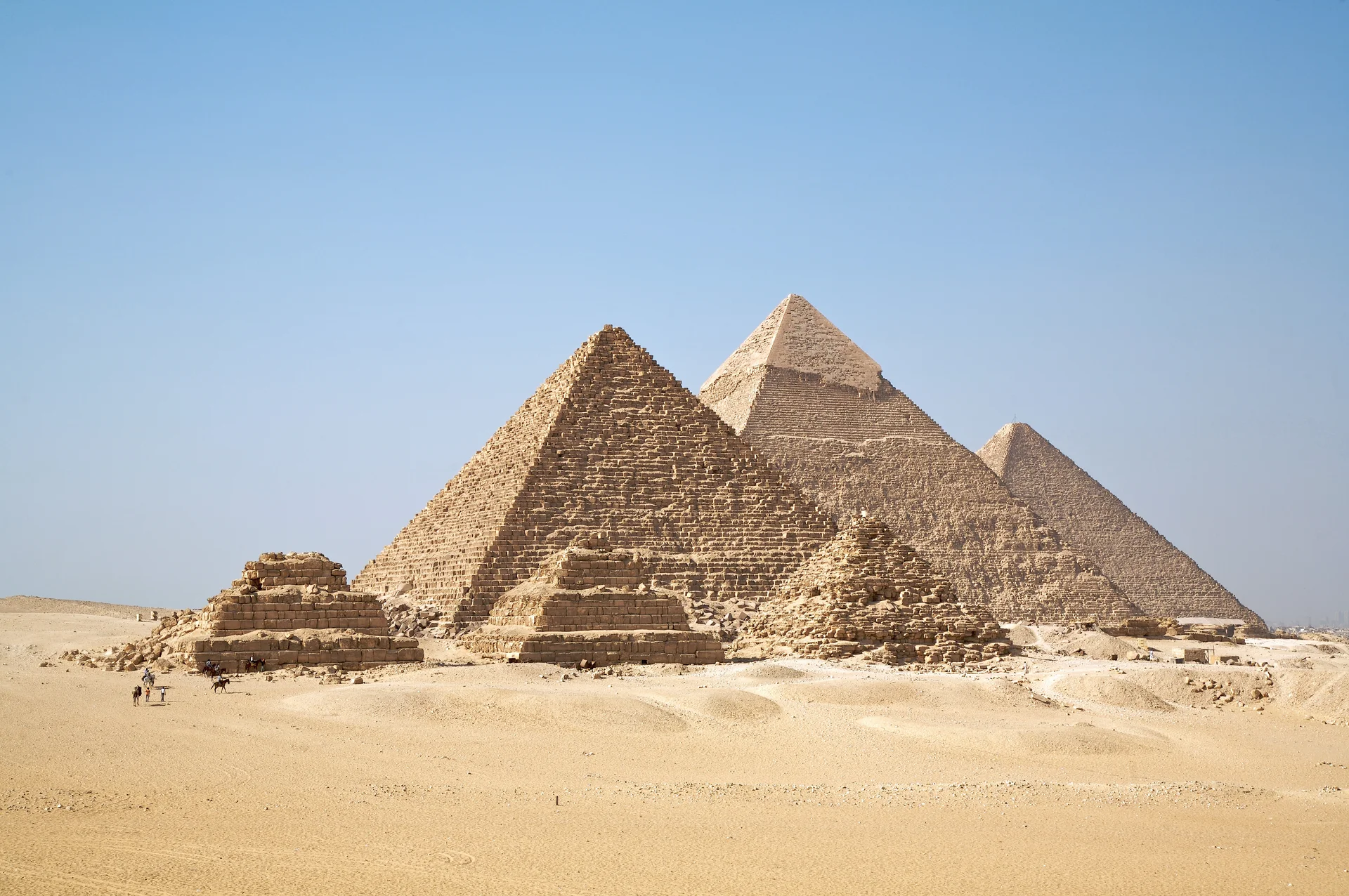 The three main pyramids of Giza illuminated by golden sunset light on the desert plateau, with the Great Pyramid of Khufu prominently featured