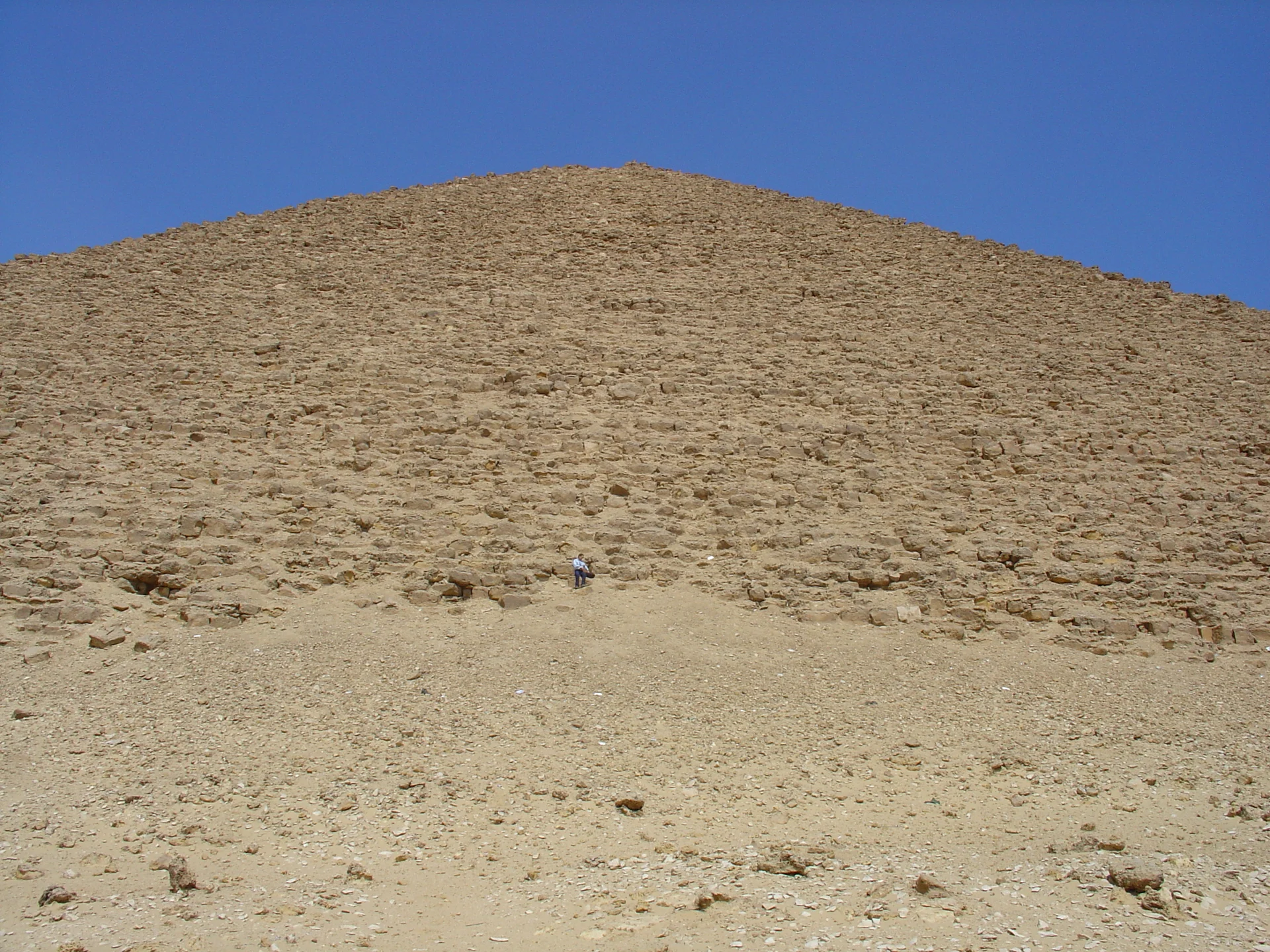 The Red Pyramid at Dahshur rising from the desert, showing the reddish limestone exposed after its white casing was removed, Egypt's first true smooth-sided pyramid