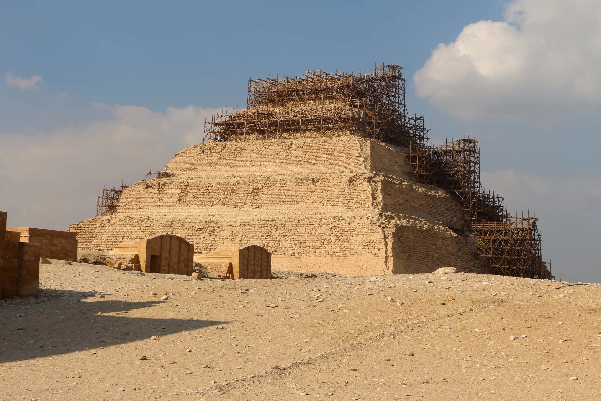 The Step Pyramid of Djoser at Saqqara rising in six distinctive tiers against the desert sky, showing the world's first monumental stone building