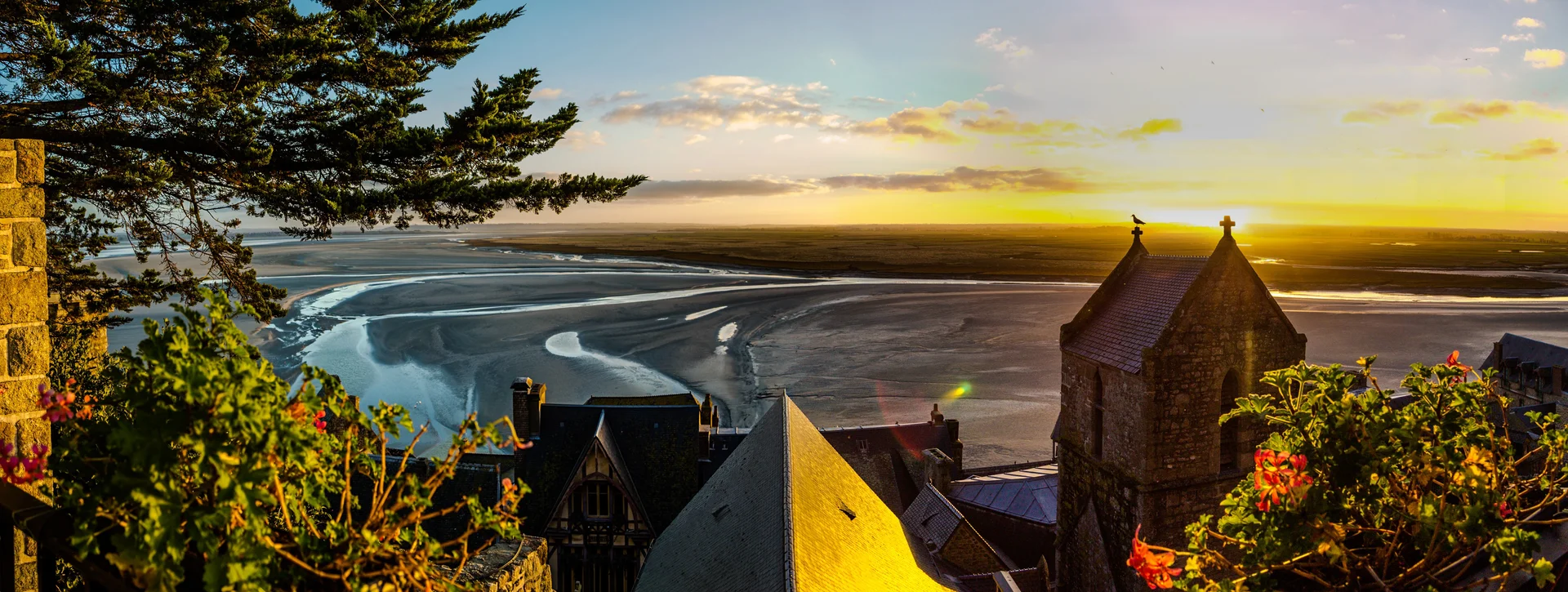 Wide panoramic view of the Bay of Mont-Saint-Michel at low tide showing vast tidal flats with the abbey in the distance