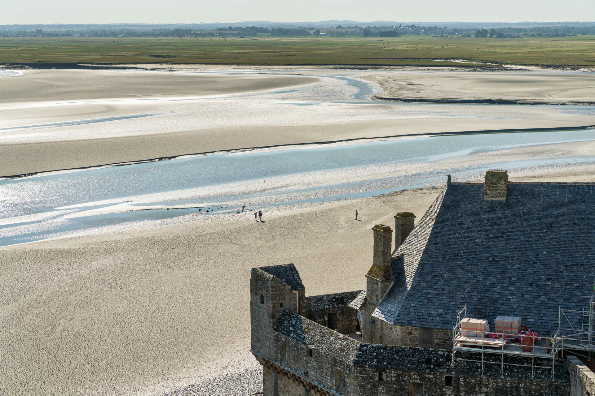 Panoramic view of Mont-Saint-Michel medieval ramparts and defensive walls during tidal change, showing the stone fortifications protecting the abbey with bay in background