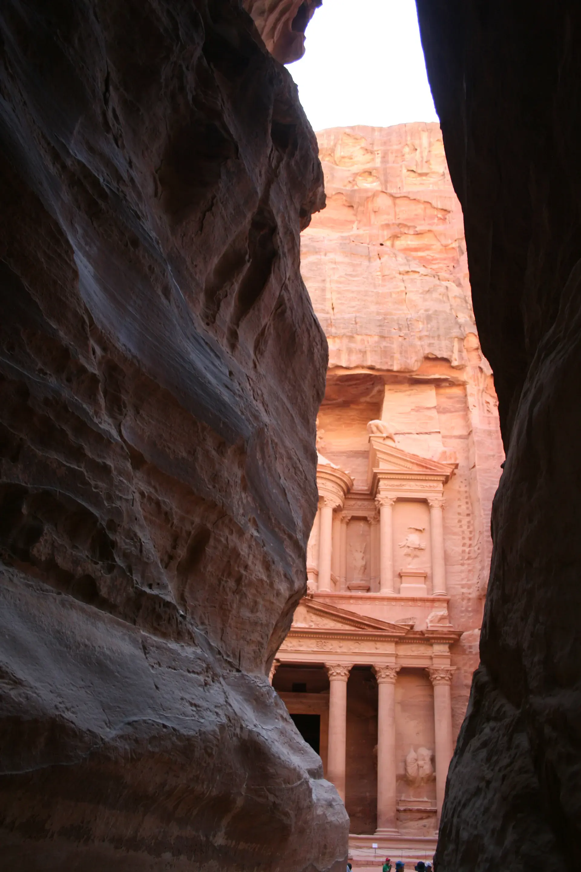 Detailed view of the Treasury's ornate facade showing intricate Nabataean carved stonework with classical columns and decorative elements in rose-red sandstone