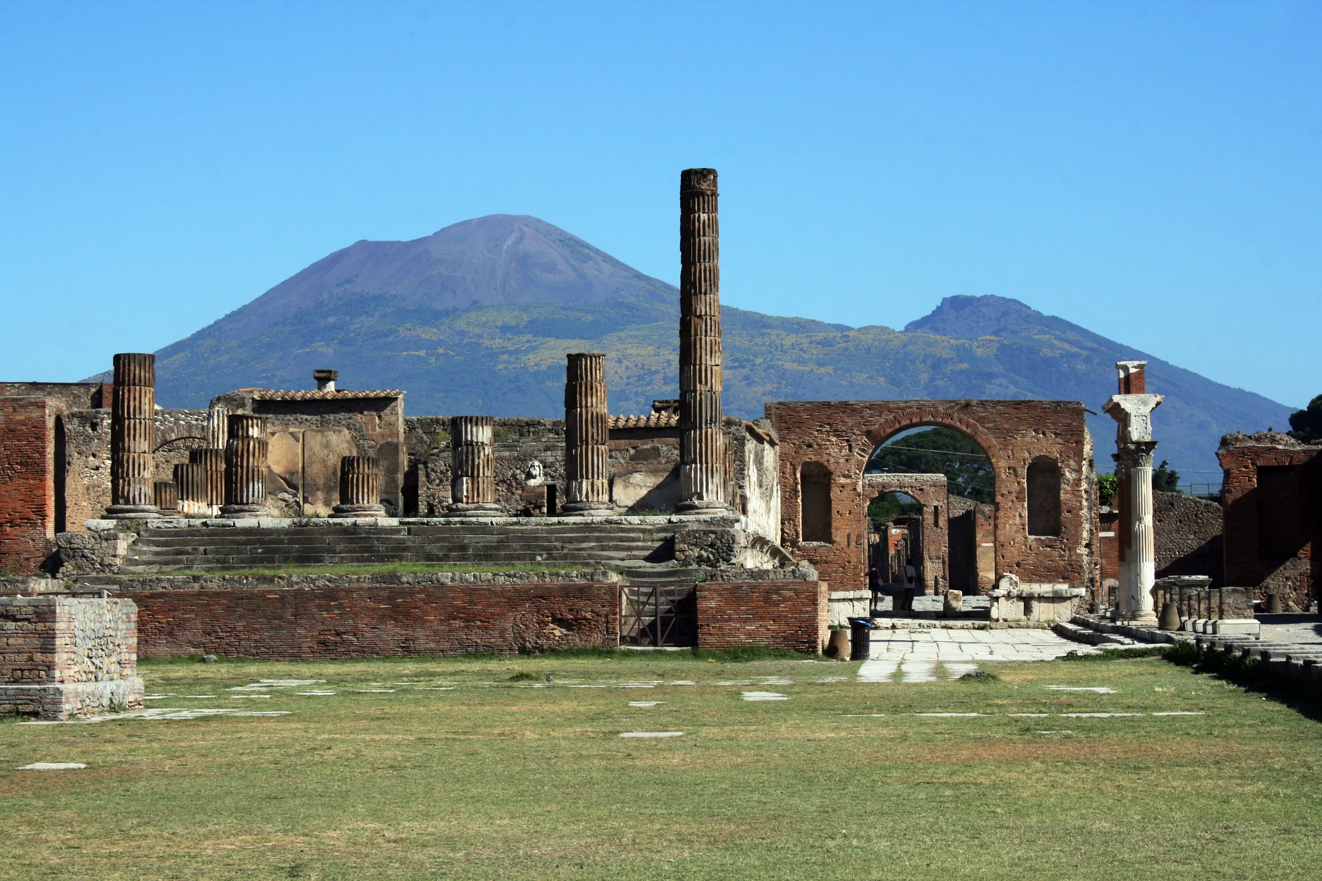 View of ancient Roman ruins at Pompeii showing stone columns, walls, and structures preserved by volcanic ash from Mount Vesuvius