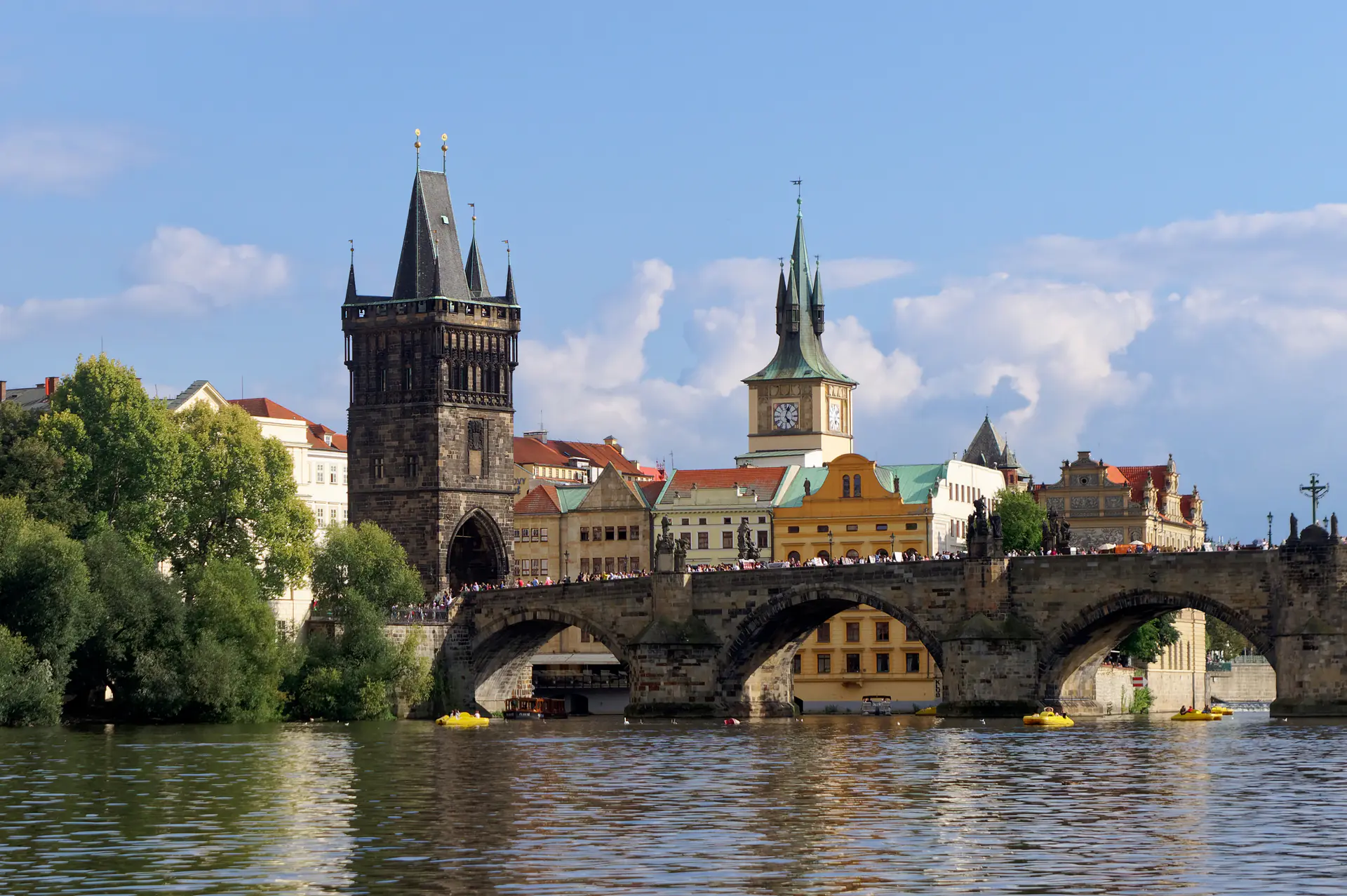 Puente de Carlos cruzando el río Moldava con estatuas barrocas siluetadas contra el cielo matutino y el Castillo de Praga visible al fondo