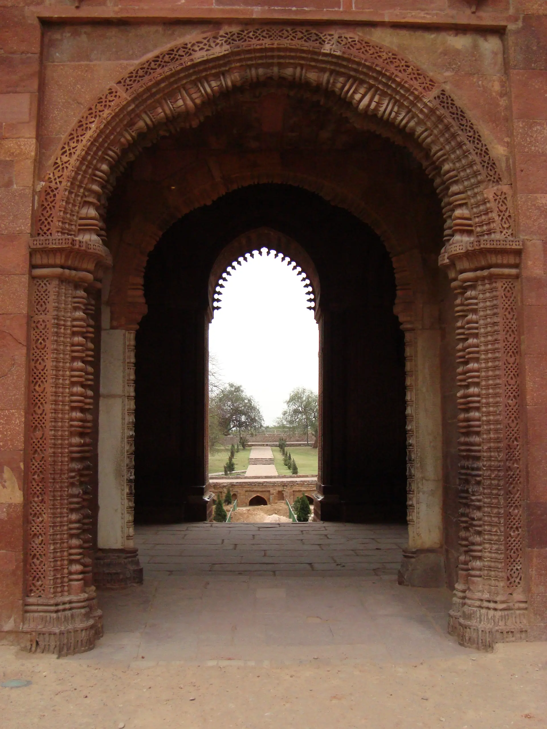 The elegant Alai Darwaza gateway showing red sandstone with white marble inlay, horseshoe arches, and intricate Islamic calligraphy
