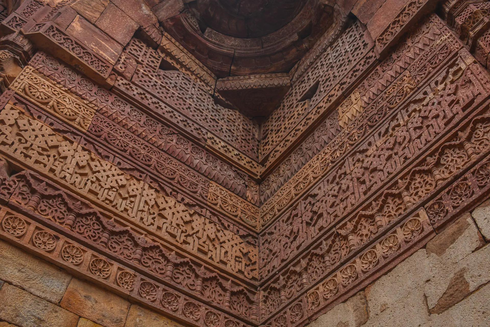 Interior of Iltutmish's tomb showing intricate stone carving with geometric patterns, calligraphy, and elaborate mihrab decoration on every surface