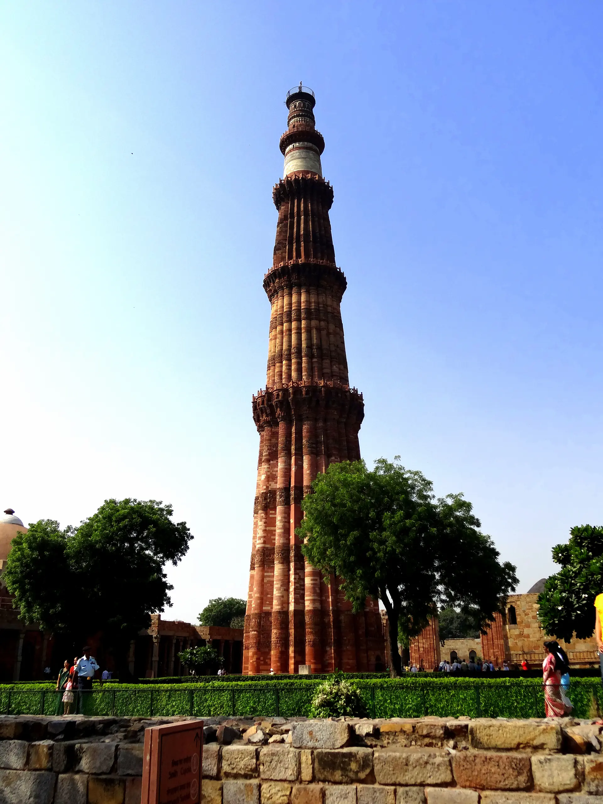Close-up view of Qutb Minar showing the intricate red sandstone carved calligraphy, geometric patterns, and distinctive tapering stories with balconies