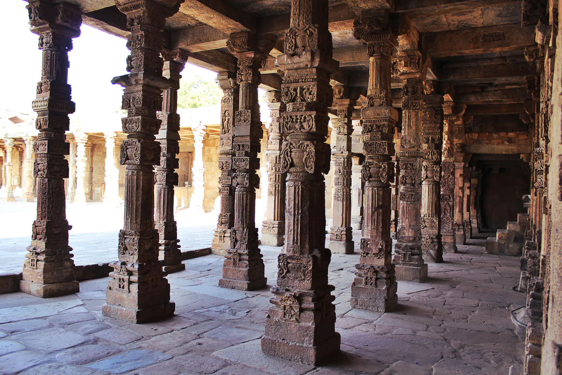 The colonnade courtyard of Quwwat-ul-Islam Mosque showing ornately carved pillars from Hindu temples repurposed for Islamic architecture