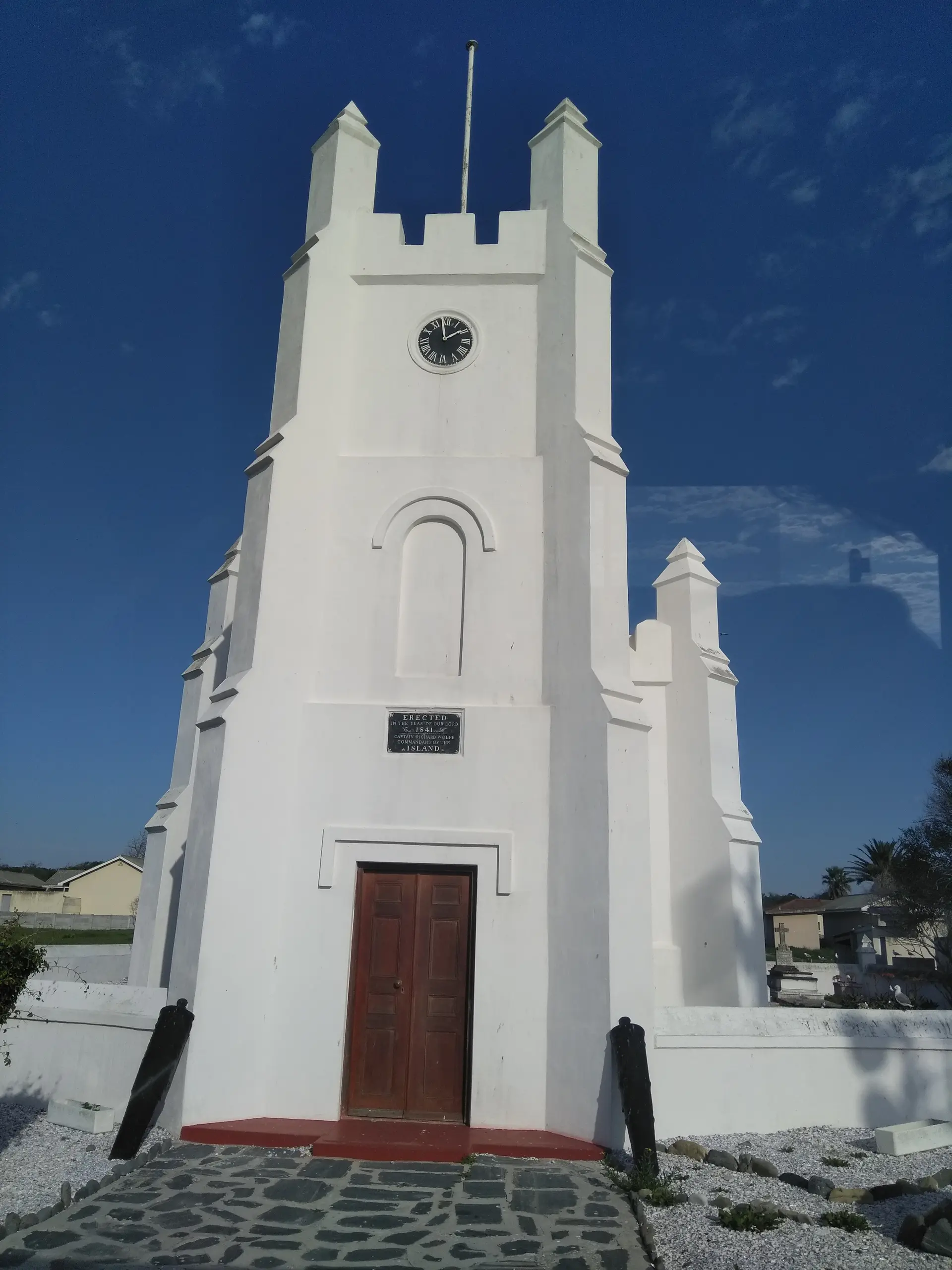 Iglesia histórica de paredes blancas en la Isla Robben con distintivo campanario contra un cielo azul