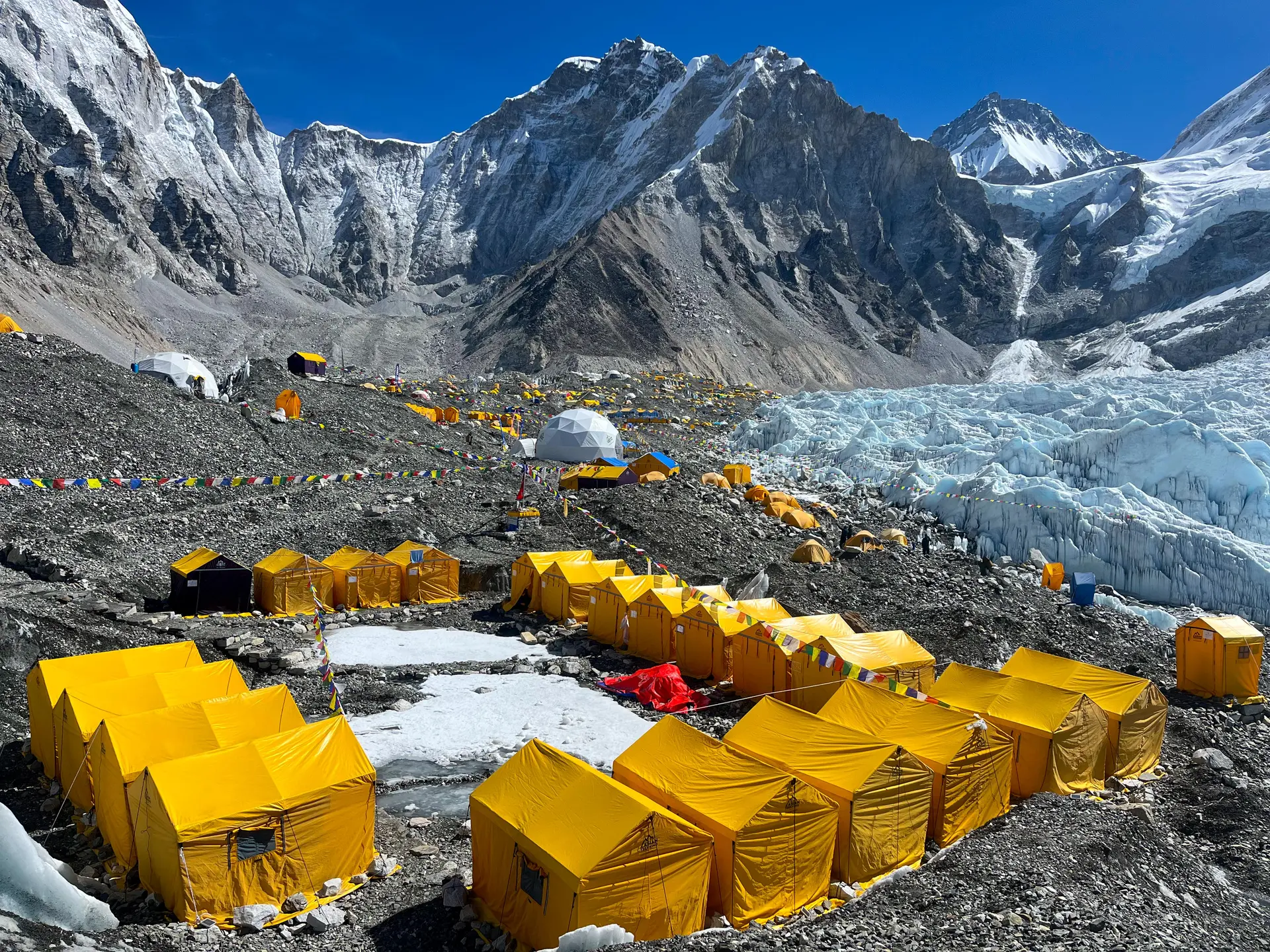 Trekkers walking along the trail towards Everest Base Camp with dramatic Himalayan peaks and glacial valley in the background