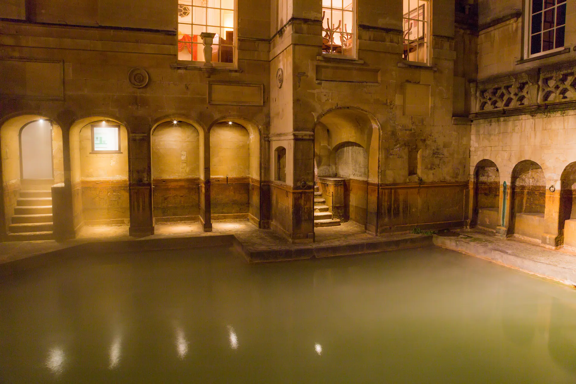 The King's Bath thermal spring in Bath, England, photographed at night showing historic stone architecture and thermal heritage