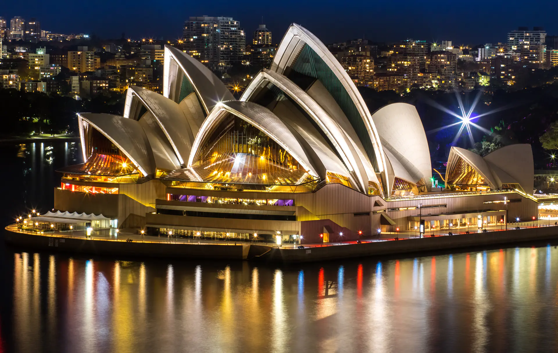 Illuminated Sydney Opera House at night with architectural details reflected in Sydney Harbour waters