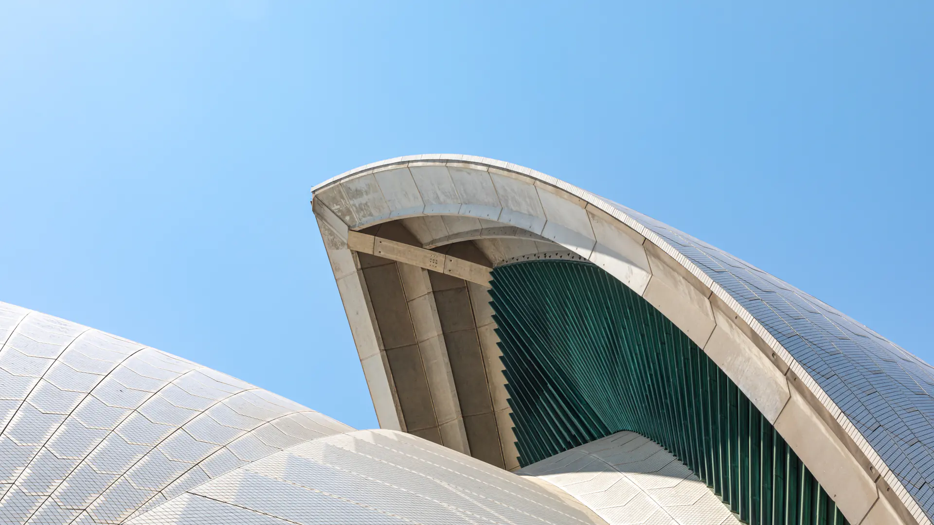 Close-up view of Sydney Opera House white concrete shell structures against blue sky, showing architectural details