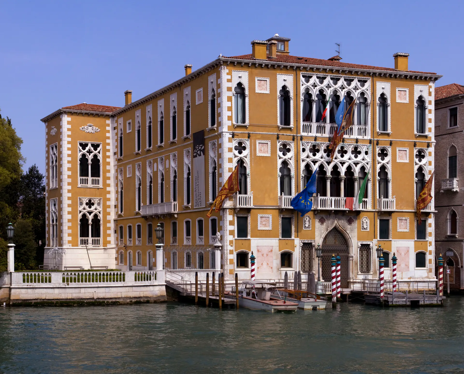 The elegant Palazzo Cavalli-Franchetti on the Grand Canal showcasing Venetian Gothic architecture with pointed arches, ornate tracery, and distinctive pink marble facade