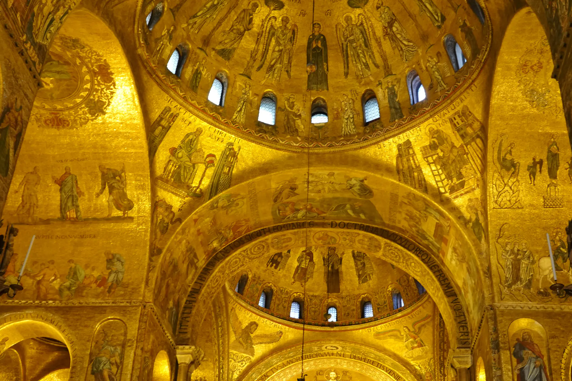 Interior view of St. Mark's Basilica showing the luminous golden Byzantine mosaics covering the dome with intricate religious imagery and ornate decoration
