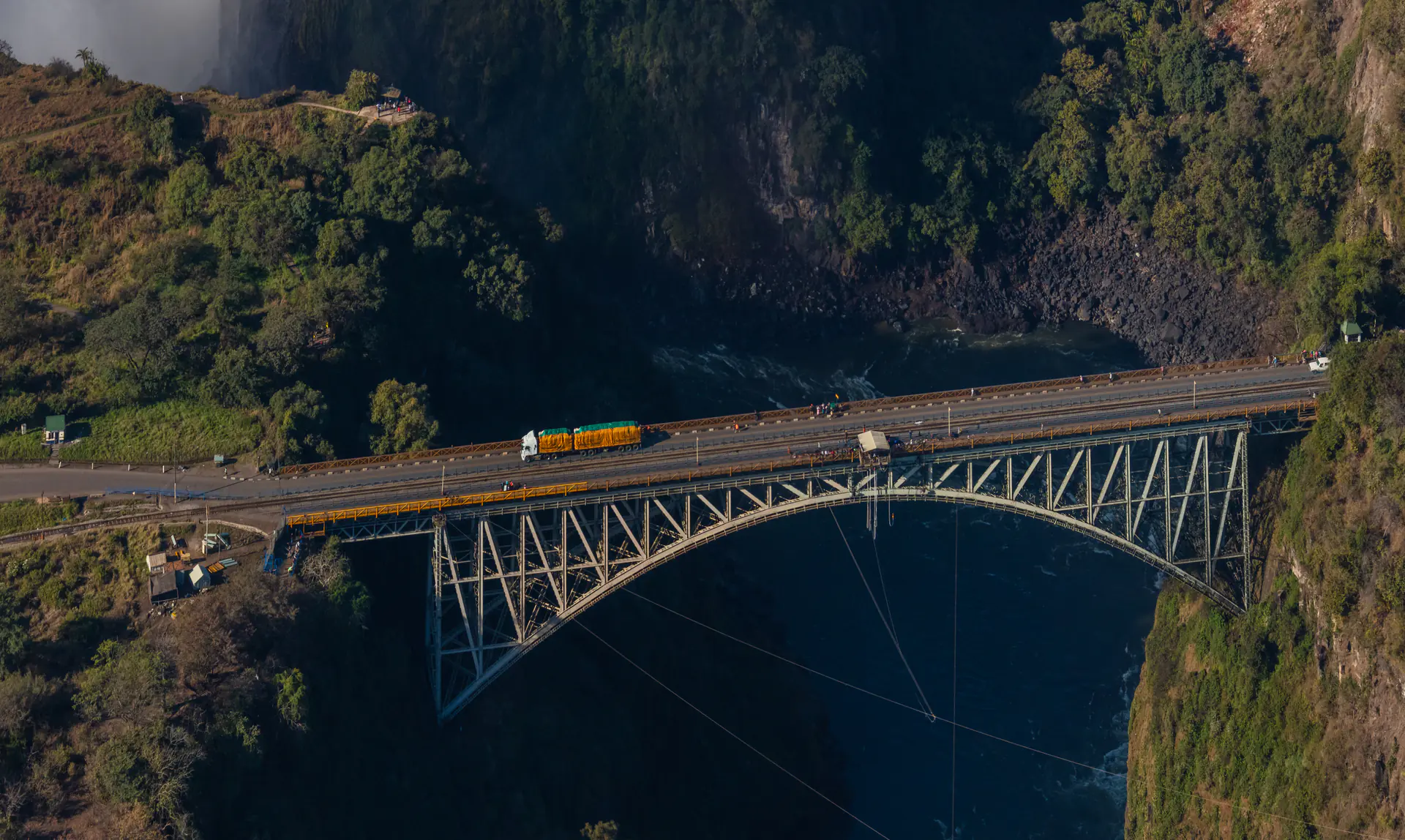 Aerial view of Victoria Falls Bridge spanning Batoka Gorge with waterfall mist visible in background