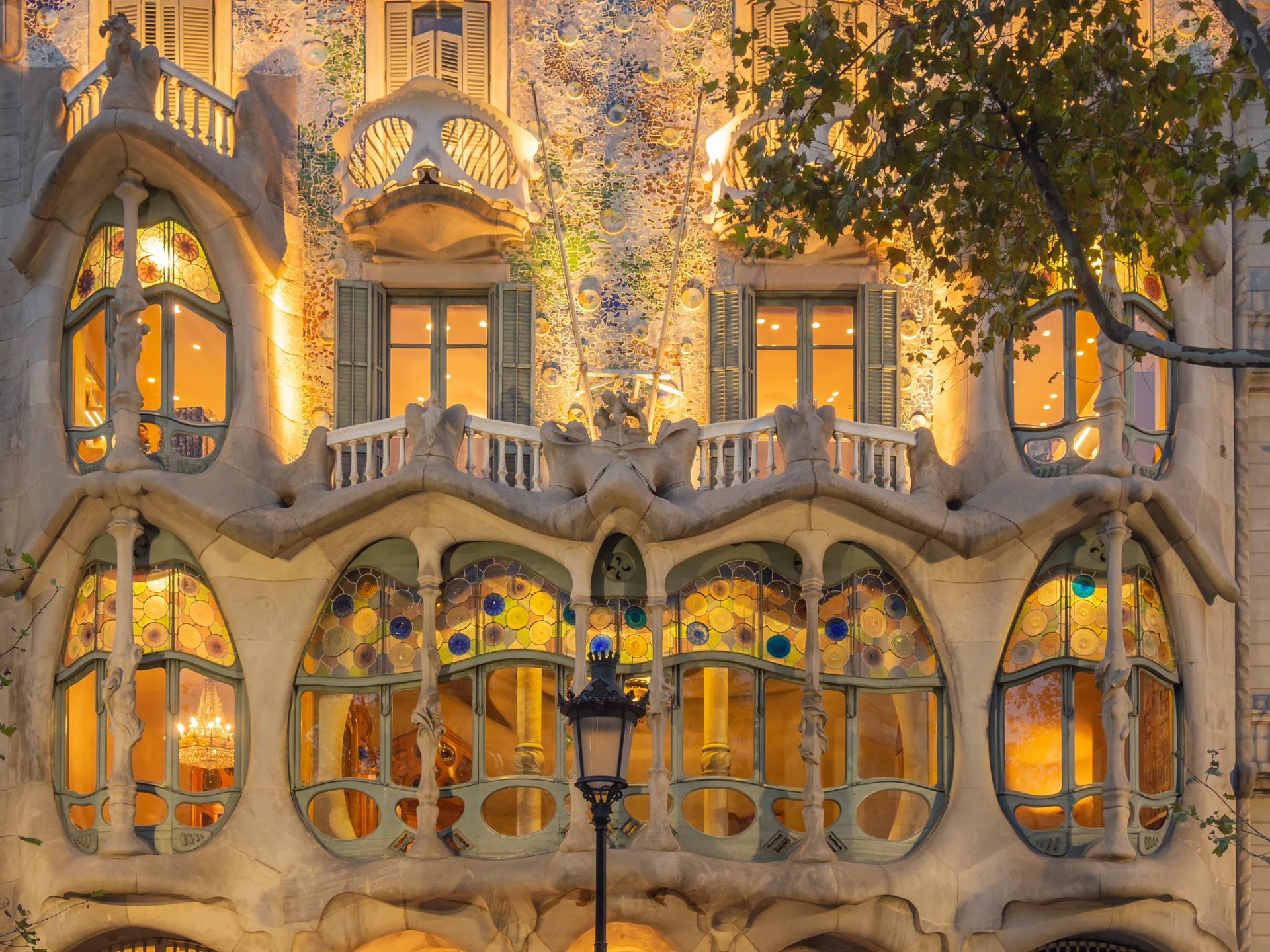 Main façade of Casa Batlló showing colourful ceramic mosaic tiles, organic sculptural balconies, and distinctive undulating roofline