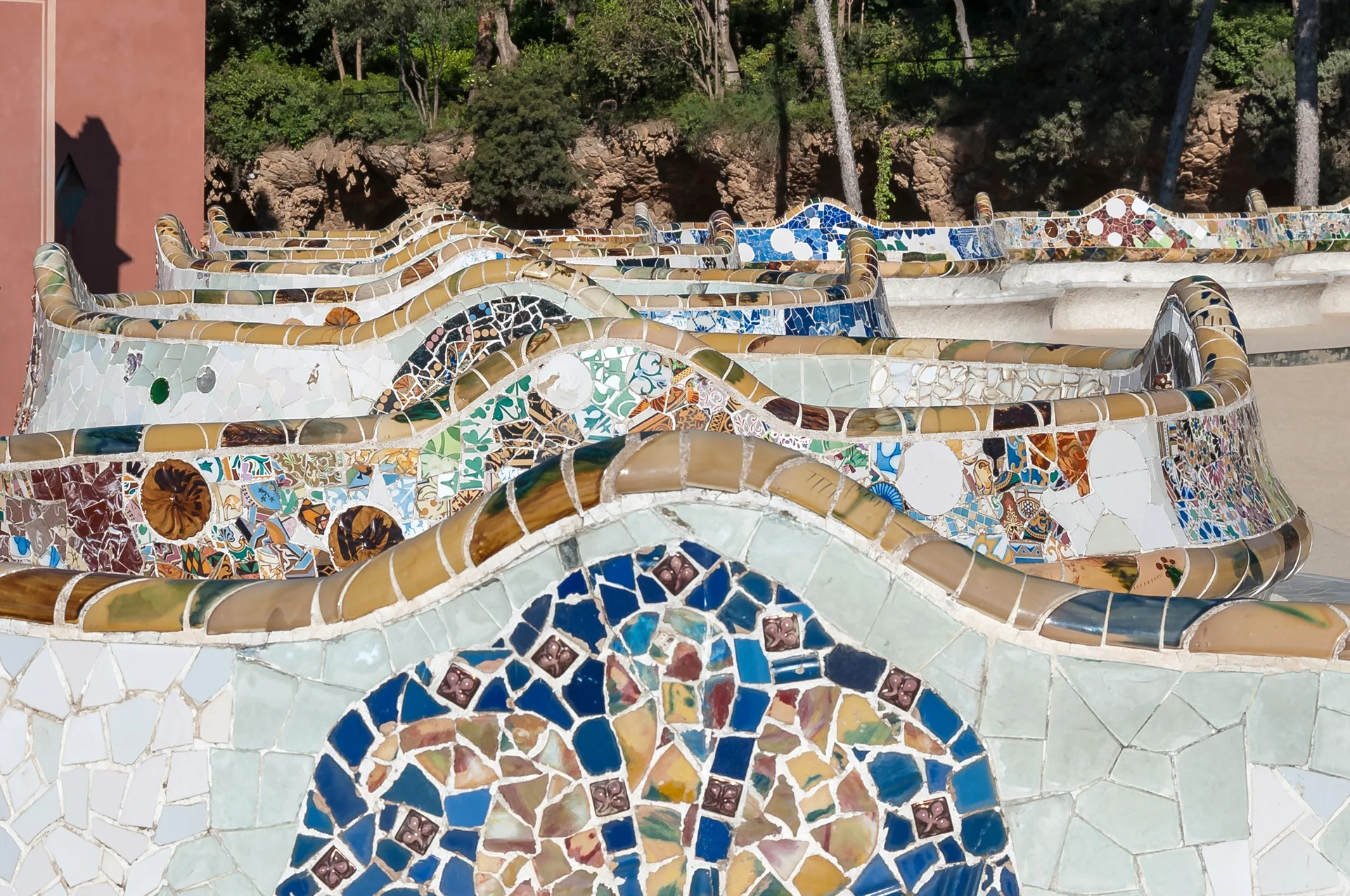 Colourful mosaic serpentine bench at Park Güell showing the undulating wavelike arrangement with intricate ceramic tile details
