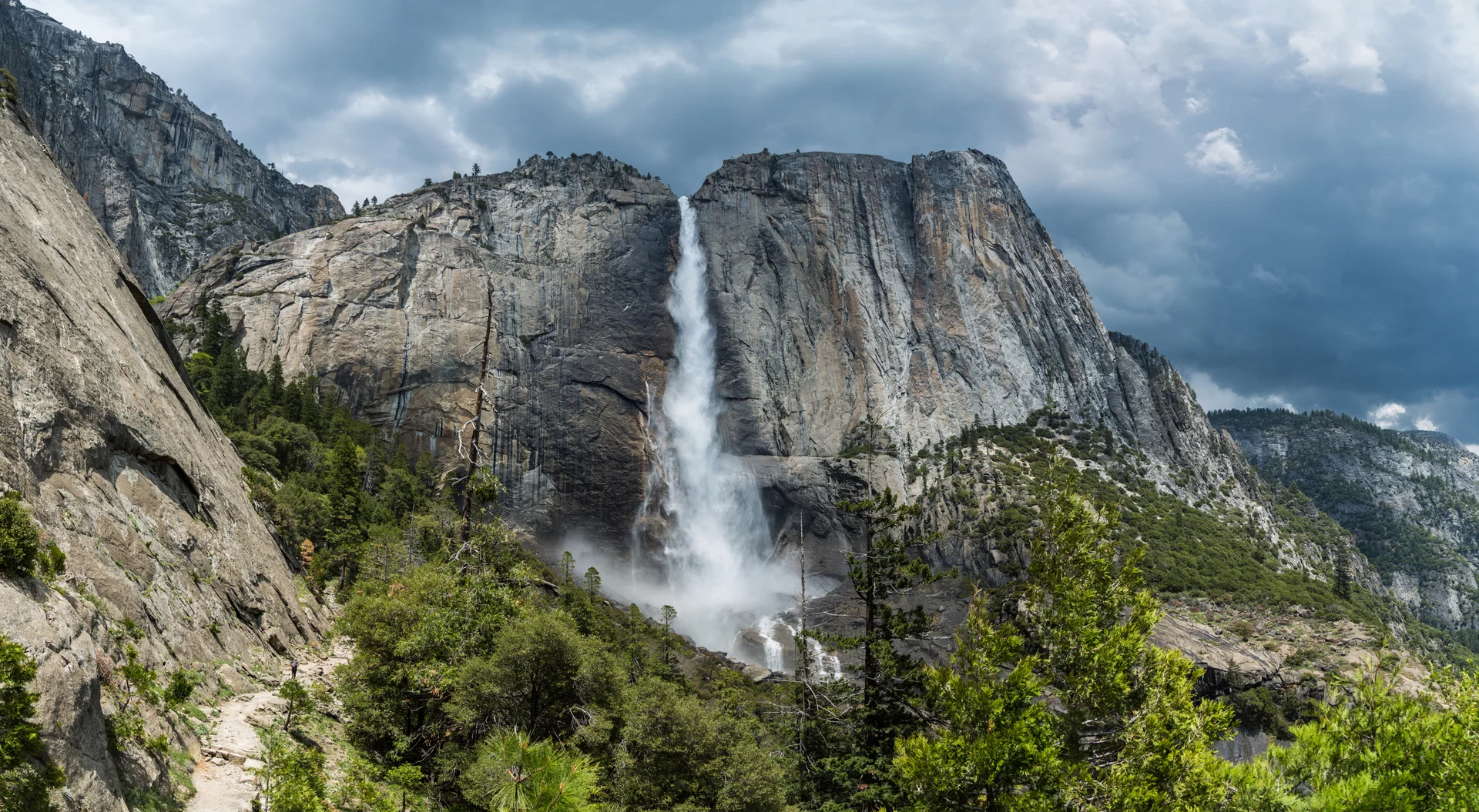 Spectacular Yosemite Falls showing complete three-tier cascade during peak spring flow with mist and rainbow effects